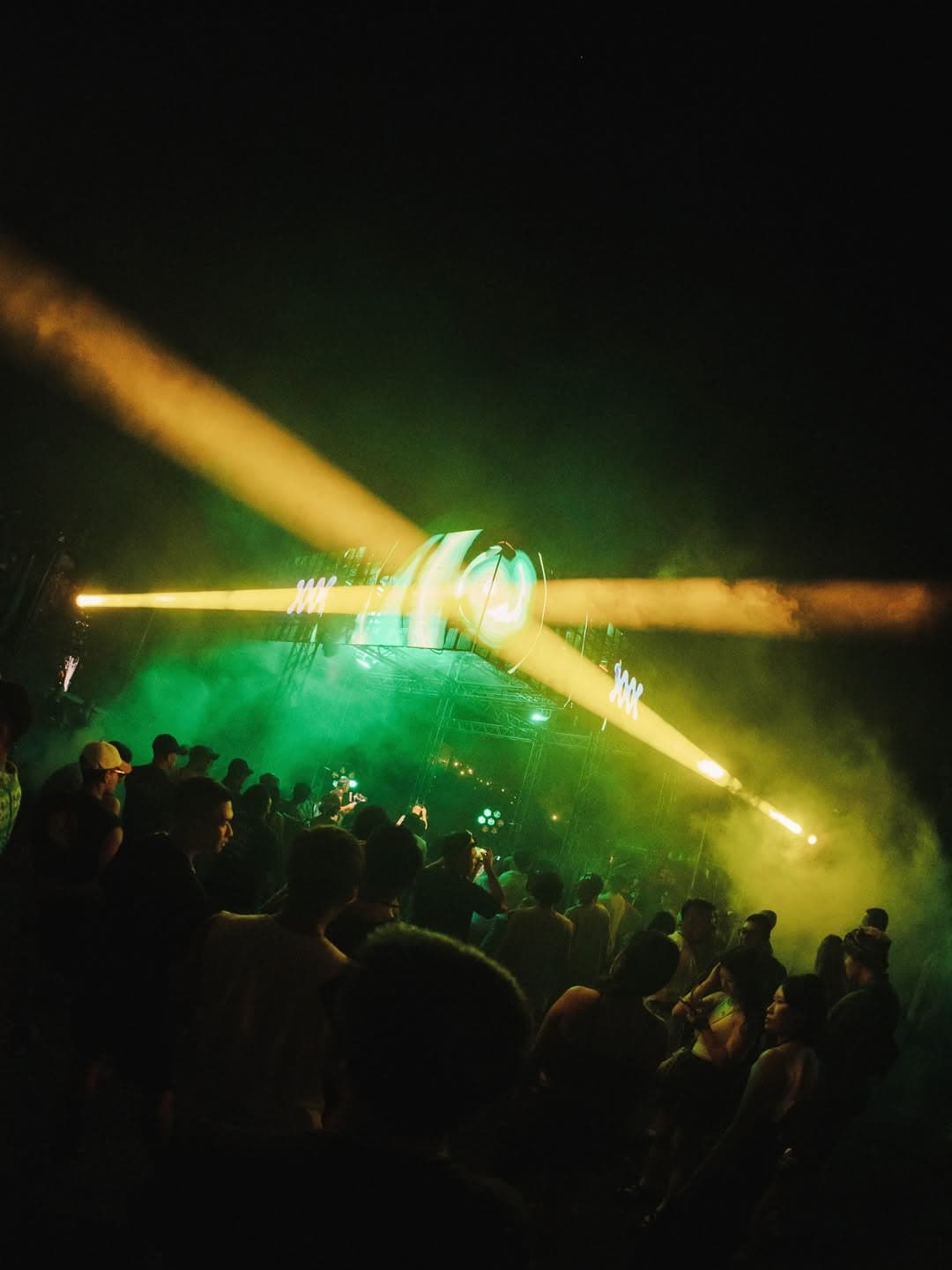 Crowd under crossing yellow lasers at the Mirage main stage at night