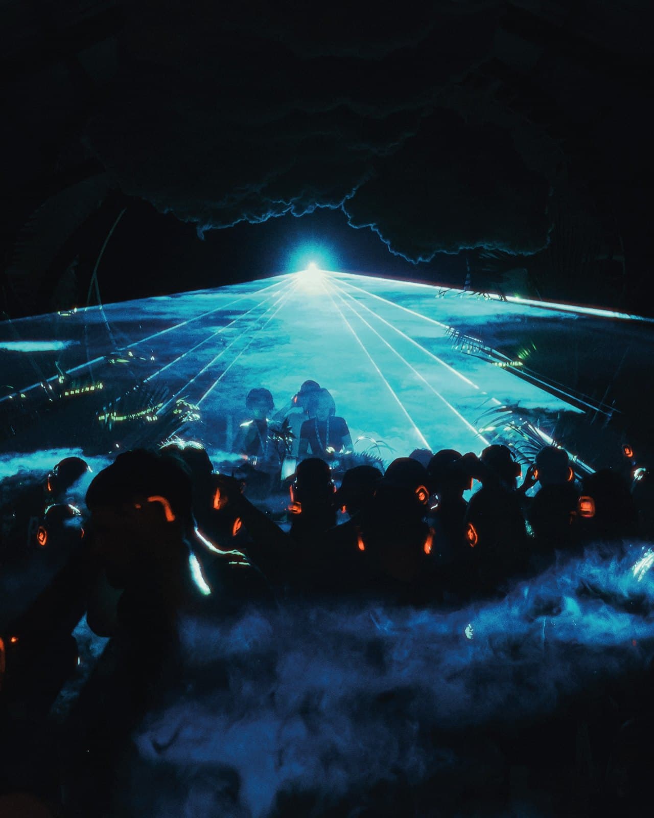 Blue laser fan over the crowd at Mirage, headphones glowing orange